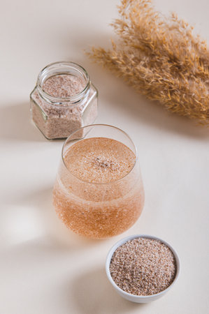 Psyllium in a glass of water, in a bowl in a jar on the table vertical view