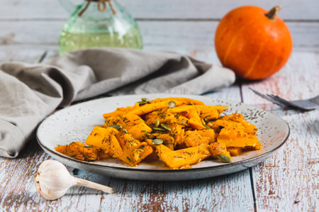 Spicy salad with fried pumpkin, garlic and herbs on a plate on the tableの写真素材