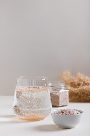 A glass of water and psyllium husk on the table for health vertical viewの写真素材