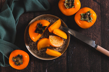Fresh ripe sliced persimmon on a plate on the table top viewの写真素材