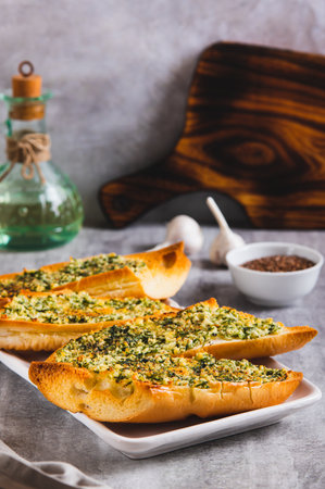 Baked baguette with butter, garlic and dill on a plate on the table vertical viewの写真素材