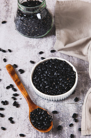 Fresh black beans in a bowl and in a jar on the table vertical viewの写真素材