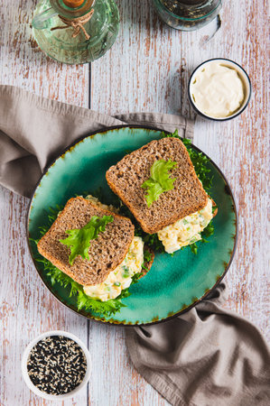 Eggs, avocado on lettuce leaves on toast on a plate on the table top and vertical viewの写真素材