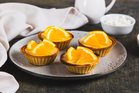 Mini baked tarts with cottage cheese and orange on a plate on the table