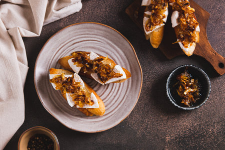 Snack sandwiches with brie cheese and caramelized onions on a plate on the table top viewの写真素材
