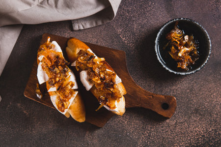 Sandwiches with creamy brie cheese and caramelized onions on a wooden board top viewの写真素材