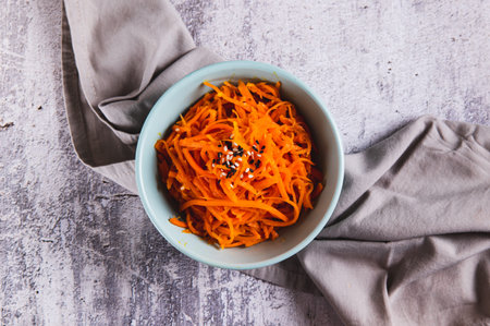 Close up of korean carrots with sesame seeds in a bowl on the table top viewの写真素材