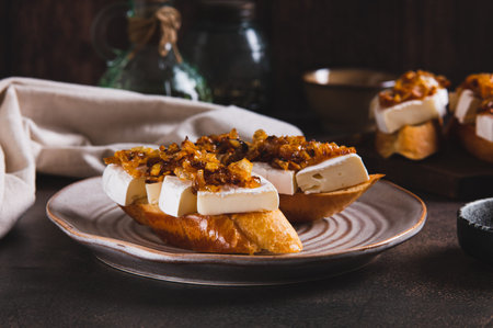 Snack sandwiches with brie cheese and caramelized onions on a plate on the tableの写真素材