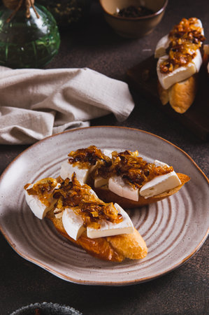 Toasts with creamy brie cheese and caramelized onions on a plate on the table vertical viewの写真素材