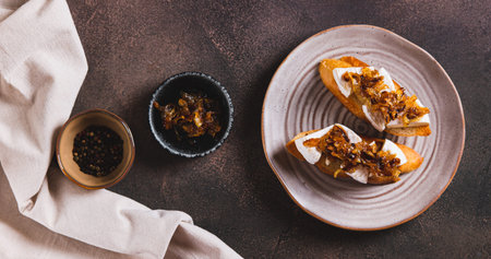 Toasts with creamy brie cheese and caramelized onions on a plate top viewの写真素材