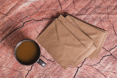 A cup of coffee and craft envelopes for writing paper letters on a table top view