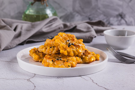 Delicious corn fritters with herbs on a plate on the tableの写真素材