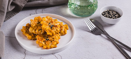 Delicious corn fritters with herbs on a plate on the table web bannerの写真素材