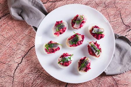 Close up of egg halves stuffed with herring under a fur coat on a plate on the table top viewの写真素材