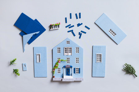 Details for assembling a miniature house model on a blue background, top view