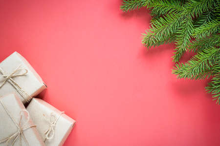 gifts in eco-friendly craft packaging for the holiday and fir spruce on a red background with copy space.の写真素材