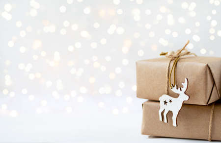 gifts of eco-friendly material and wooden deer toy on white background with lights and copy spaceの写真素材