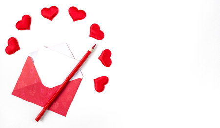 red envelope and pencil with red hearts on white background with copy space.