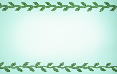 light blue background with a place for text and branches of green leaves on the borders.