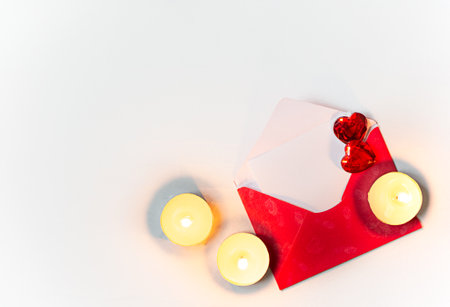 red envelope with red heart and candles on white background with copy space