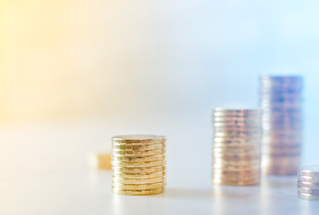 Golden coins in high stacks on yellow and blue background with copy space.