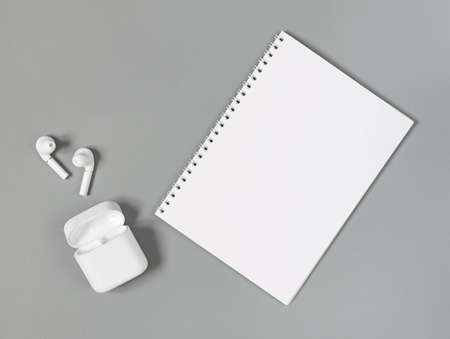 white wireless headphones and notepad on a gray background.の写真素材