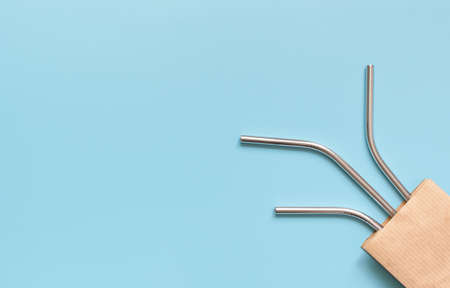 reusable steel drinking straws in craft bag on blue background.