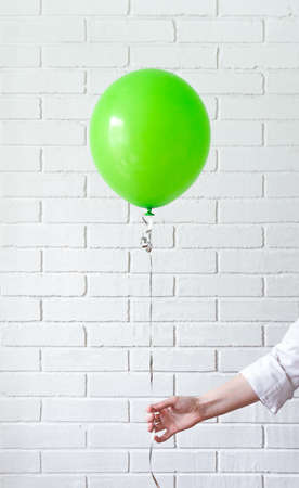 hand holds the green balloon on the ribbon.の写真素材