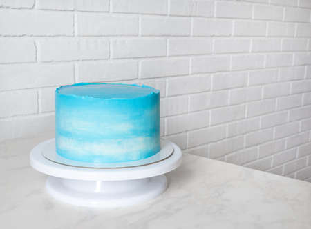 bright blue cake on a stand with copy space. cloud pattern on cream cake