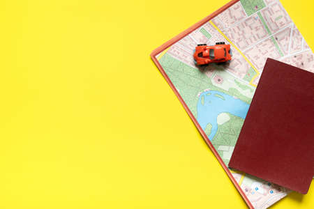 passport, map, toy car on a yellow background. flat lay with copy space.