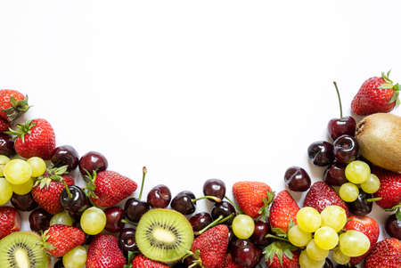 horizontal frame from juicy fruits. strawberries, cherries, kiwi, lime and grapes on white background.の写真素材