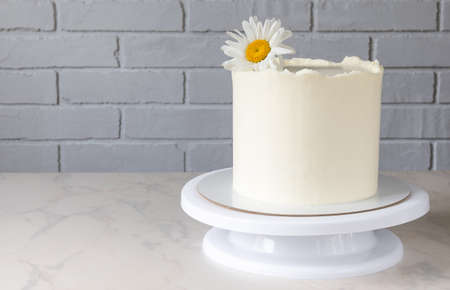 tall white cake on a stand with a decor of a chamomile flowerの写真素材