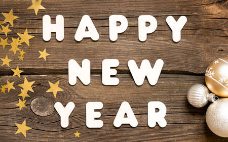 Happy New Year Letters and balls and stars on wooden background.