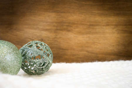 green christmas baubles on white blanket with copy space on wooden wallの写真素材