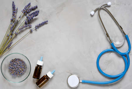 Alternative medicine herbs of lavender, oil and stethoscope on grey backgroundの写真素材