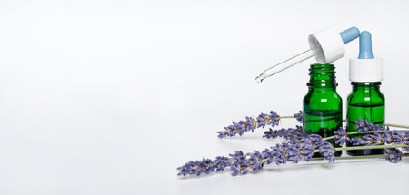 green bottle with aroma oil and lavender flowers on white backgroundの写真素材