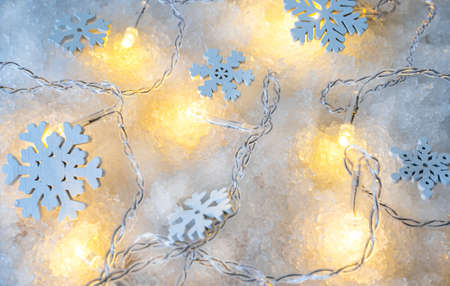 wooden snowflakes, garland lights on a pile of snow.の写真素材