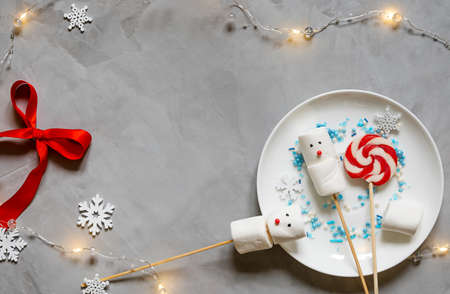 little snowmens from marshmallows on sticks on a white plate. lollipops and snowflakes. christmas food.の写真素材