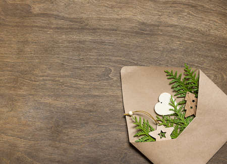 envelope with thuja and wooden toys on a wooden table.