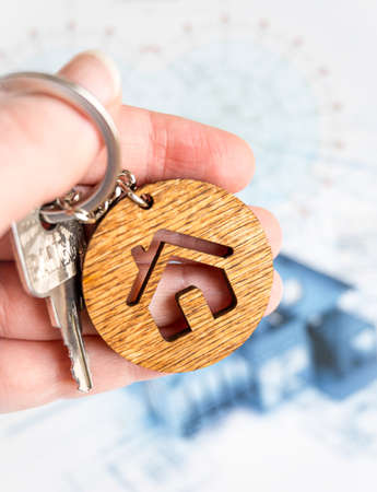 concept mortgage. hand holds key and keychain-house from the purchased housing