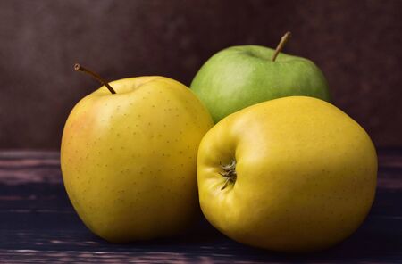 Yellow and green apples on a brown textural background, still life, with a soft pleasant light, close-upの写真素材