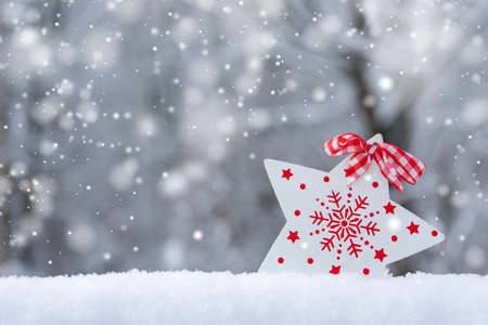 Christmas card with snow, snowflakes and a white star on a blurred natural background. Happy New Year, festive mood. Winter background. Copy space.の写真素材