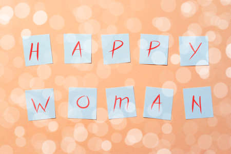 Ready lettering "happy woman" on white squares of paper on a pink background.の写真素材
