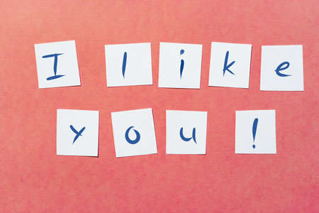 Ready-made lettering "I like you" on white squares of paper on a pink background.の写真素材