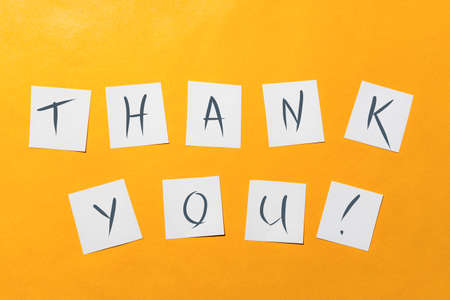 Ready-made inscription "thank you" on white squares of paper on a gold background.の写真素材