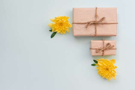 Gift box with kraft paper and yellow chrysanthemum flowers on a light blue background. Flat lay for father's day concept.の写真素材