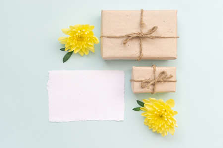 Gift box with kraft paper and yellow chrysanthemum flowers on a light blue background. Flat lay for father's day concept.の写真素材