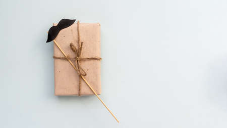 Gift box with kraft paper with a mustache on a light blue background. Flat lay for father's day concept.の写真素材