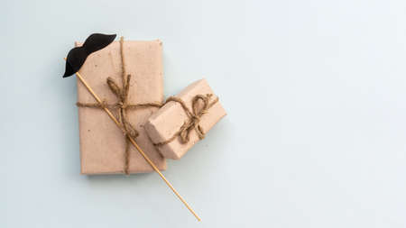 Gift box with kraft paper with a mustache on a light blue background. Flat lay for father's day concept.の写真素材