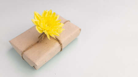 Gift box with craft paper and a yellow chrysanthemum flower on a light blue background. Flat lay for father's day concept.の写真素材